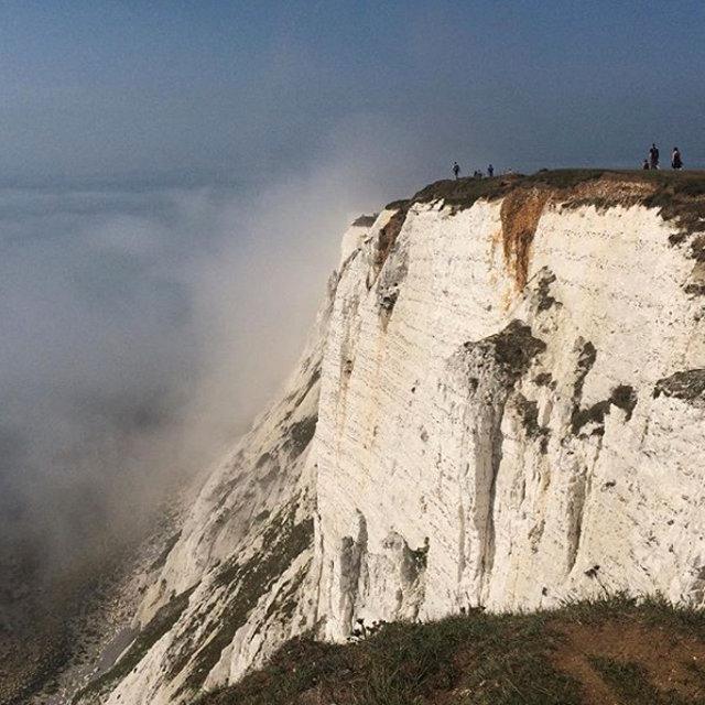 People stand on a cliff at Beachy Head amidst mist, near Eastbourne, Britain on Aug. 27, 2017. (Louisa Neale via REUTERS)