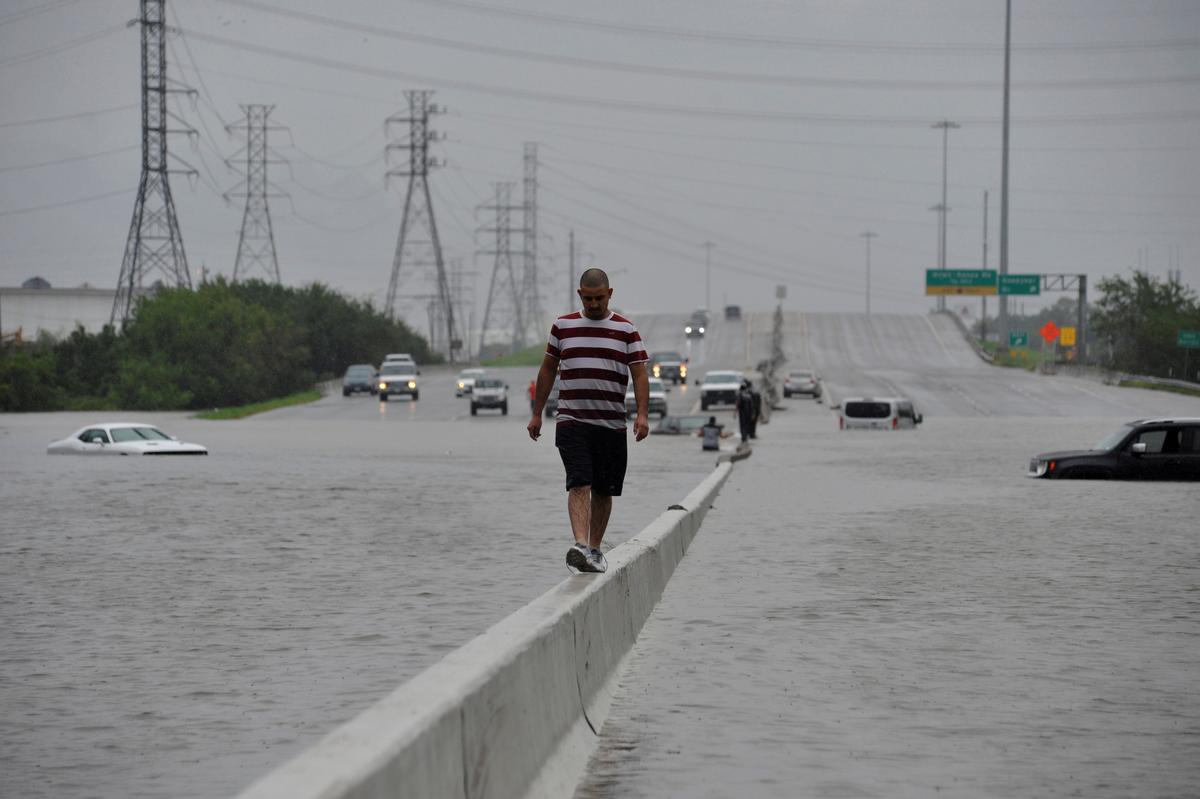 A stranded motorist escapes floodwaters on Interstate 225 after Hurricane Harvey inundated the Texas Gulf coast with rain causing mass flooding, in Houston, Texas on Aug. 27, 2017. (REUTERS/Nick Oxford)