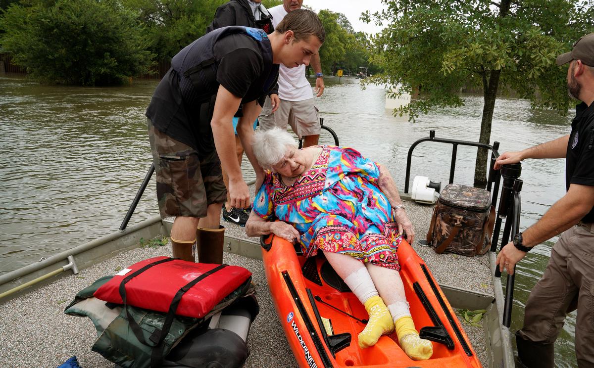 Sterling Broughton is helped from a kayak onto a rescue boat from her flooded home in Dickinson, Texas on Aug. 27, 2017. (REUTERS/Rick Wilking)