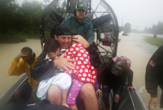 Dean Mize holds children as he and Jason Legnon use an airboat to rescue people from homes that are inundated with flooding from Hurricane Harvey on Aug. 28, 2017 in Houston, Texas. (Joe Raedle/Getty Images)