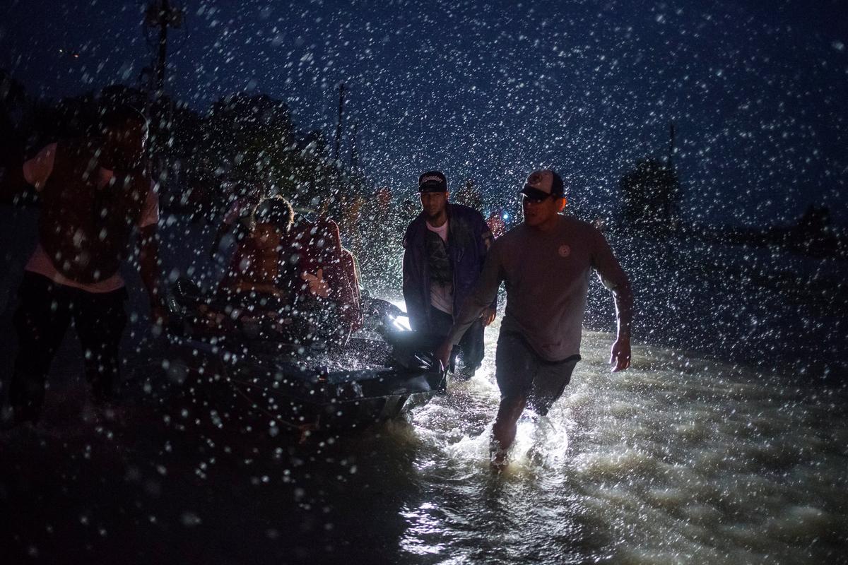 Samaritans help push a boat with evacuees to high ground during a rain storm caused by Tropical Storm Harvey along Tidwell Road in east Houston, Texas, U.S. August 28, 2017. (REUTERS/Adrees Latif)