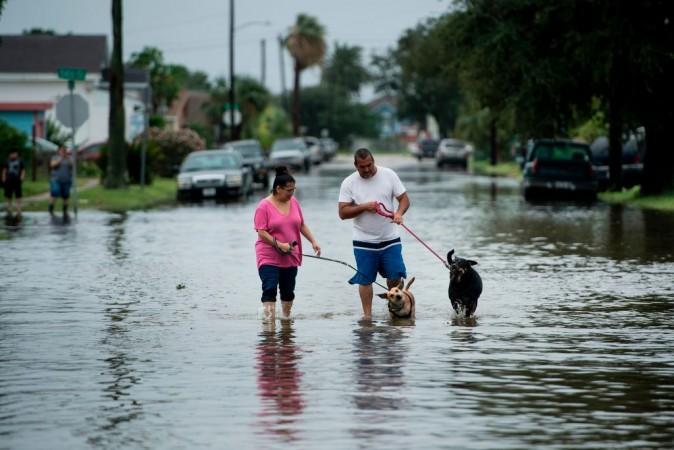 People walk on flooded streets as the effects of Hurricane Harvey are seen Aug. 27, 2017, in Galveston, Texas. Hurricane Harvey left a trail of devastation Saturday after the most powerful storm to hit the U.S. mainland in over a decade slammed into Texas, destroying homes, severing power supplies, and forcing tens of thousands of residents to flee. (Brendan Smialowski/AFP/Getty Images)