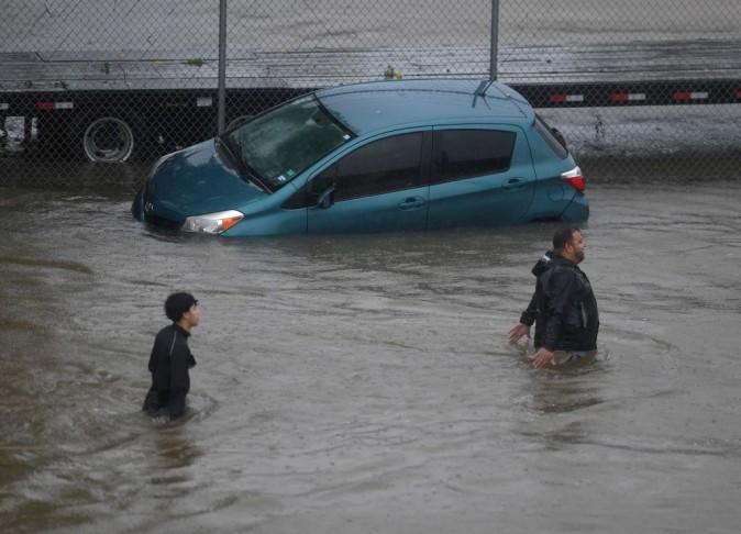 People evacuate through water past an abandoned car after Hurricane Harvey caused heavy flooding in Houston, Texas on August 28, 2017. Rescue teams in boats, trucks and helicopters scrambled Monday to reach hundreds of Texans marooned on flooded streets in and around the city of Houston before monster storm Harvey returns. (MARK RALSTON/AFP/Getty Images)