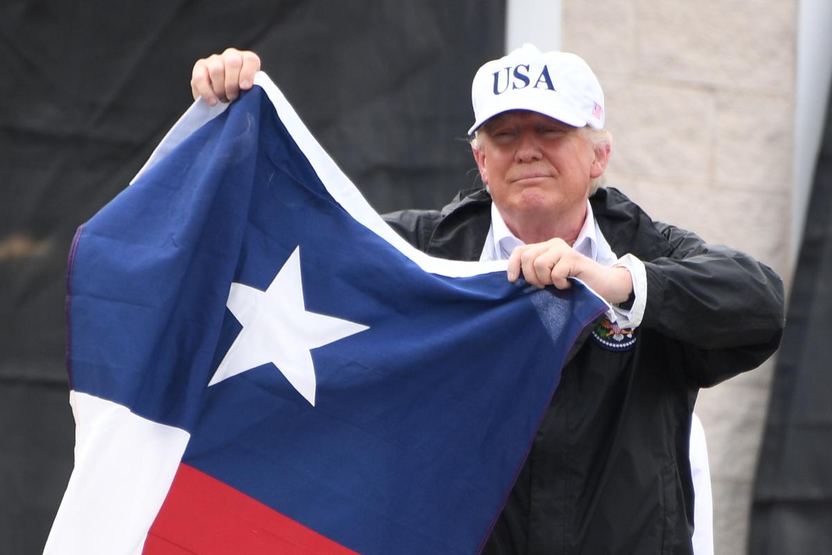 President Donald Trump holds a Texas state flag outside of a fire house in Corpus Christi, Texas, on Aug. 29, where he received a briefing on the response to Hurricane Harvey. Trump thanked hundreds of people who had gathered outside of the fire station and said that "Texas can handle anything." (JIM WATSON/AFP/Getty Images)