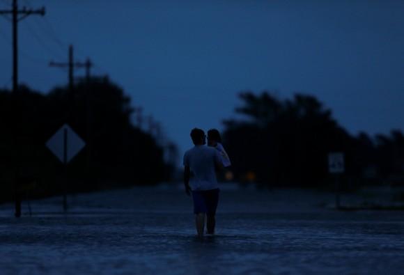 Ethan holds his 2-year-old daughter Zella as they walk through flood waters from Tropical Storm Harvey in Iowa, Calcasieu Parish, Louisiana, U.S., on August 29, 2017. (Reuters/Jonathan Bachman)
