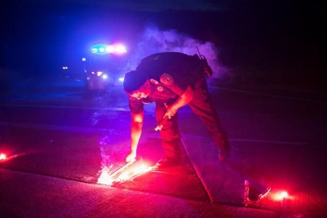 A police officer lays down a safety flare while blocking the road leading to the Arkema SA plant, which was hit by floods caused by Tropical Storm Harvey near Crosby, Texas, on Aug. 31, 2017. (Adrees Latif/Reuters)
