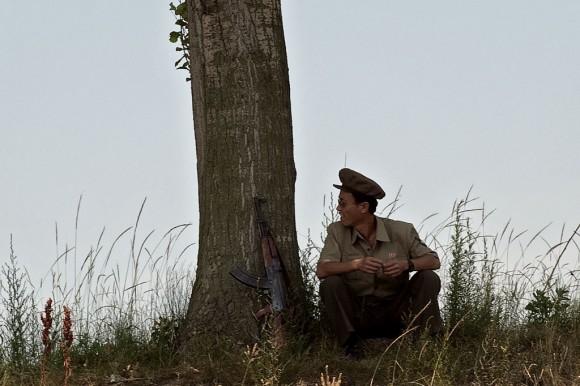 A North Korean soldier sits near a tree on the banks of the Yalu River near Sinuiju, opposite the Chinese border city of Dandong on July 5, 2017. (Nicolas Asfouri/AFP/Getty Images)