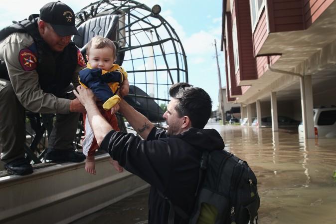 Michael Boyd passes his son Skylar over to a rescue worker as they are evacuated on an airboat from their apartment complex after it was inundated with water following Hurricane Harvey on August 30, 2017 in Houston, Texas. (Scott Olson/Getty Images)