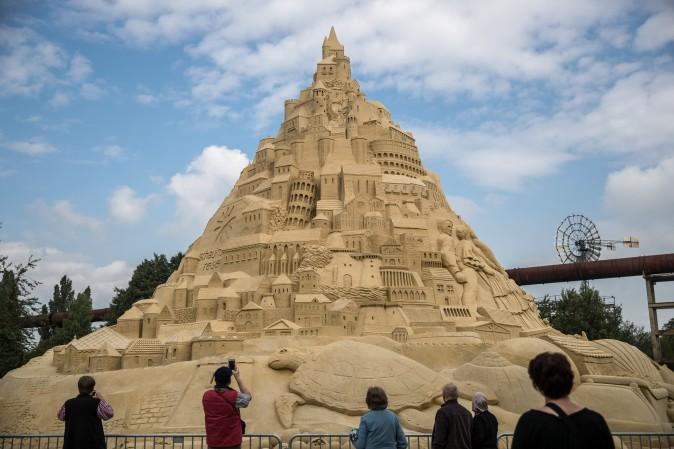 Visitors stand near the Sandburg sandcastle in Duisburg, Germany, on Sept. 1, 2017. A local travel agency commissioned the building of the sandcastle and sought to beat the previous world record of 14.84 meters and make it with 16.68 meters to set the new Guinness Book of World Record. The Sandburg took three weeks to build and is made from 3,500 tons of sand. (Maja Hitij/Getty Images)