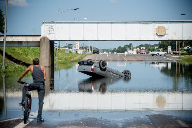 A bicyclist stops to look at a truck flipped into floodwater in Port Arthur in Houston on on Sept. 1.<br/>Houston was limping back to life on Friday one week after Hurricane Harvey slammed into America's fourth-largest city and left a trail of devastation across other parts of southeast Texas. (Emily Kask /AFP/Getty Images)