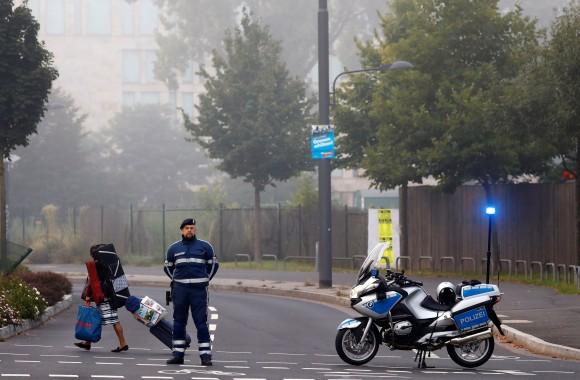 A woman carries her belongings walking past a police officer as some 60,000 people in Germany's financial capital are about to evacuate the city while experts defuse an unexploded British World War Two bomb found during renovations on the university's campus in Frankfurt, Germany, September 3, 2017. (Reuters/Kai Pfaffenbach)