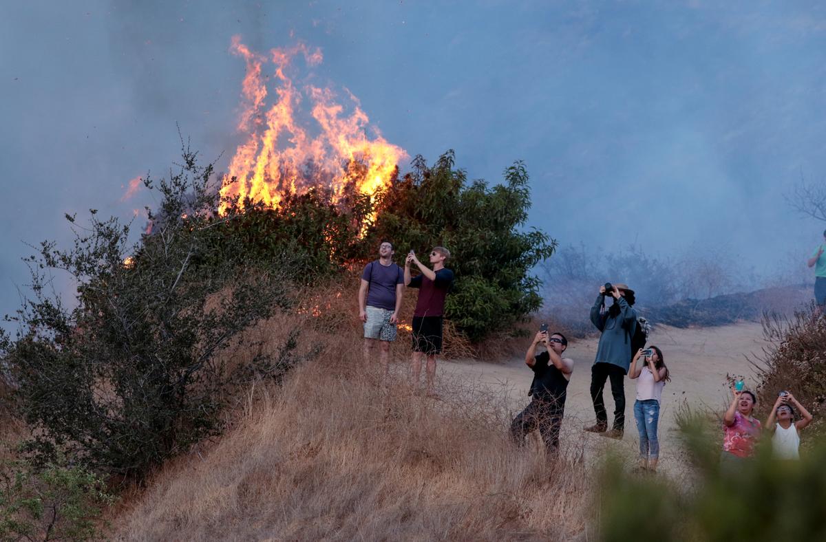 Spectators watch a helicopter fly over the La Tuna Canyon fire over Burbank. (REUTERS/ Kyle Grillot)