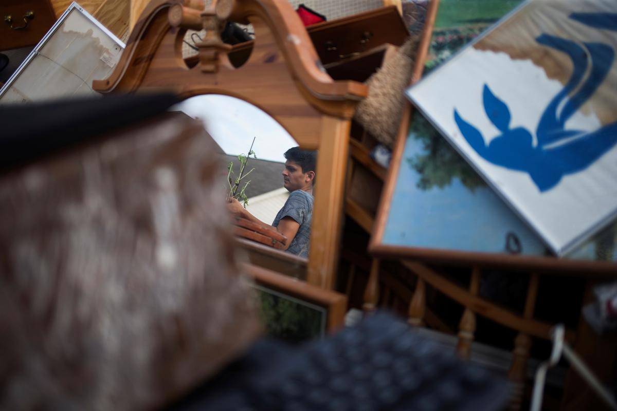 Isaac Zermeno is reflected in a mirror as he helps discard furniture from the house of a neighbor who was left flooded from Tropical Storm Harvey in Houston, Texas on Sept. 3, 2017. (REUTERS/Adrees Latif)