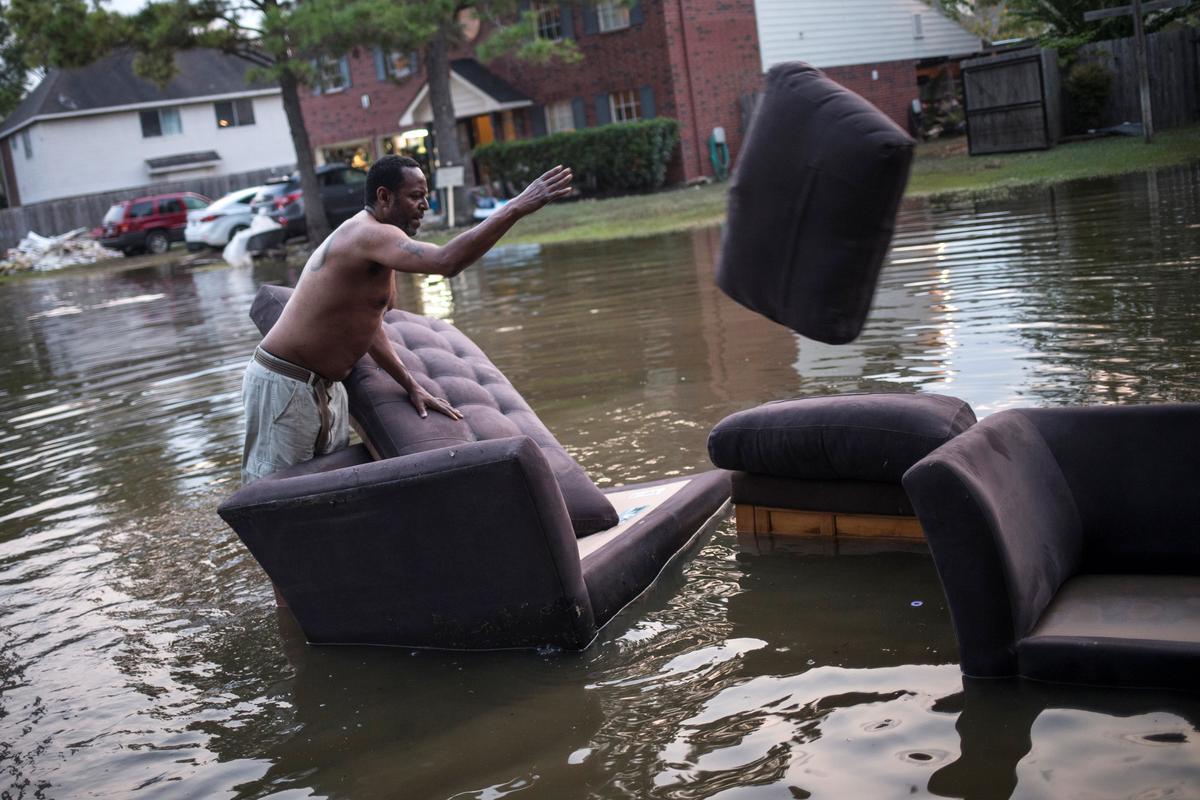 Vince Ware moves his sofas onto the sidewalk from his house which was left flooded from Tropical Storm Harvey in Houston, Texas on Sept. 3, 2017. (REUTERS/Adrees Latif)