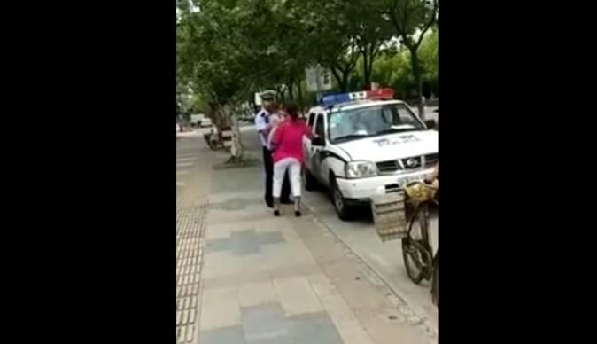 The moment before the police officer slams the woman and child to the pavement (YouTube/screenshot)