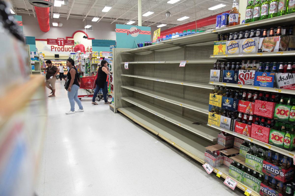 Customers walk near empty shelves that are normally filled with bottles of water after Puerto Rico Governor Ricardo Rossello declared a state of emergency in preparation for Hurricane Irma, in San Juan, Puerto Rico on Sept. 4, 2017. (REUTERS/Alvin Baez)