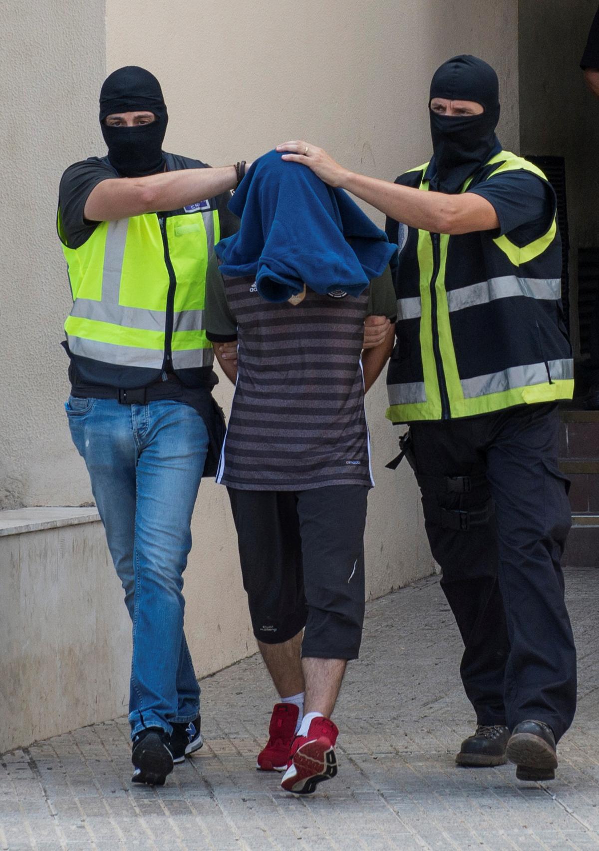 Spanish police lead a man from a police station after he was arrested for allegedly belonging to an Islamist terrorist cell that simulated decapitations in the Spanish north African enclave of Melilla on Sept. 6, 2017. (REUTERS/Jesus Blasco de Avellaneda)
