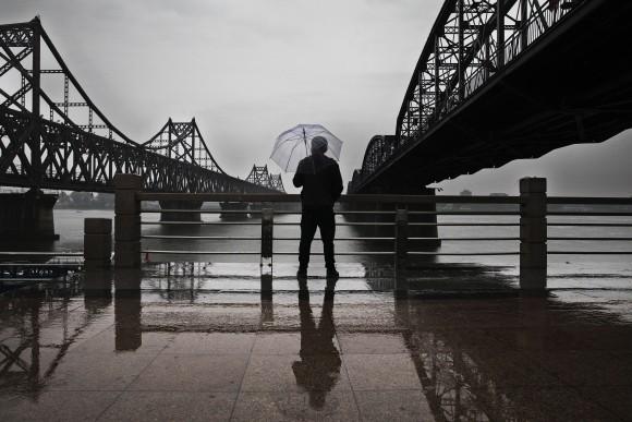 A Chinese man looks across the Yalu River at the North Korean city of Sinuiju between the Friendship Bridge (L) and the Broken Bridge that connects the two countries in from Dandong, China, on May 23, 2017. (Kevin Frayer/Getty Images)