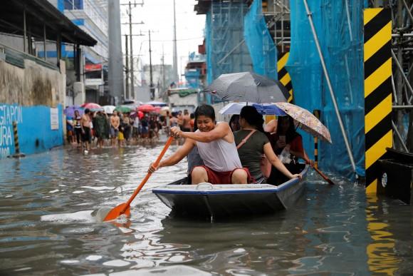 Residents use a makeshift boat to ferry commuters along floodwaters in Quezon City, Metro Manila as a storm sweeps across the main Luzon island, Philippines, September 12, 2017. (Reuters/Dondi Tawatao)