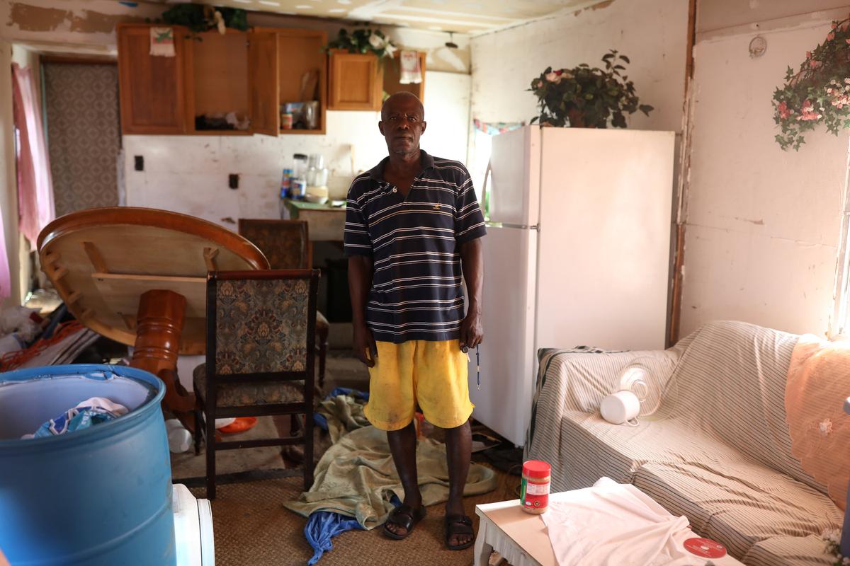 Renel Madere stands inside his mobile home, which was damaged by Hurricane Irma in Immokalee, Fla., on Sept. 12, 2017. (Reuters/Stephen Yang)