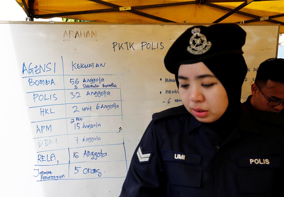 A policewoman stands next to a noticeboard accounting for manpower involved in the aftermath of a fire at religious school school Darul Quran Ittifaqiyah in Kuala Lumpur, Malaysia on Sept. 14, 2017. (REUTERS/Lai Seng Sin)