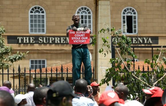A supporter of Kenya's President Uhuru Kenyatta carries a placard as they demonstrate outside the Supreme Court in protest of the nullification of Kenyatta's victory by the Supreme Court Judges in Nairobi, Kenya, September 19, 2017. (Reuters/Baz Ratner)
