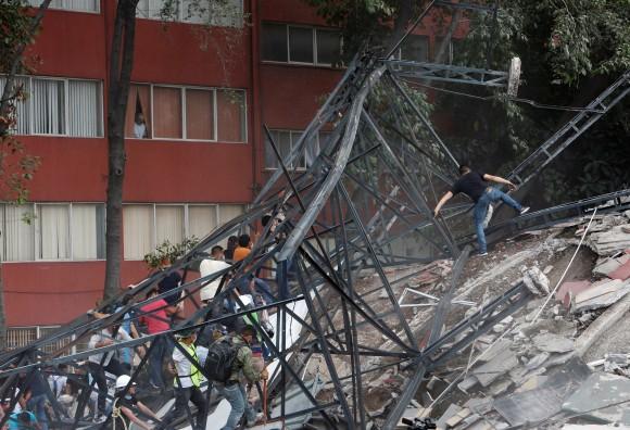 People climb over the debris of a collapsed building after an earthquake hit Mexico City on Sept. 19, 2017. (Ginnette Riquelme/Reuters)