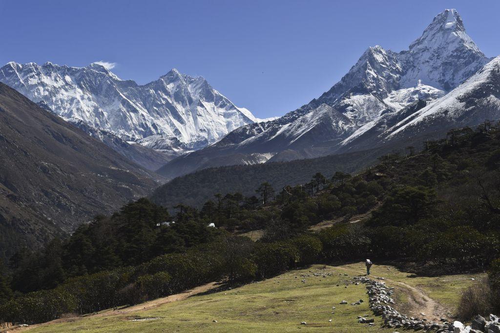 A Nepalese porter carries goods along a pathway in the Himalayas, with Mount Everest on the left, in the village of Tembuche in the Khumbu region of northeastern Nepal on April 20, 2015. (ROBERTO SCHMIDT/AFP/Getty Images)