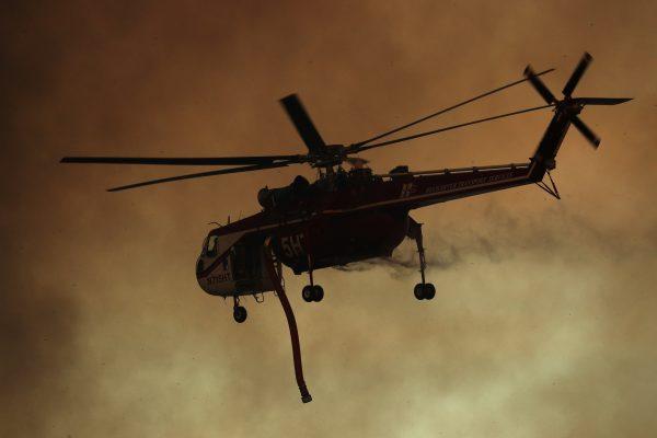 A firefighting helicopter flies in to make a water drop on a wind driven wildfire in Orange, California, U.S., Oct. 9, 2017. (Reuters/Mike Blake