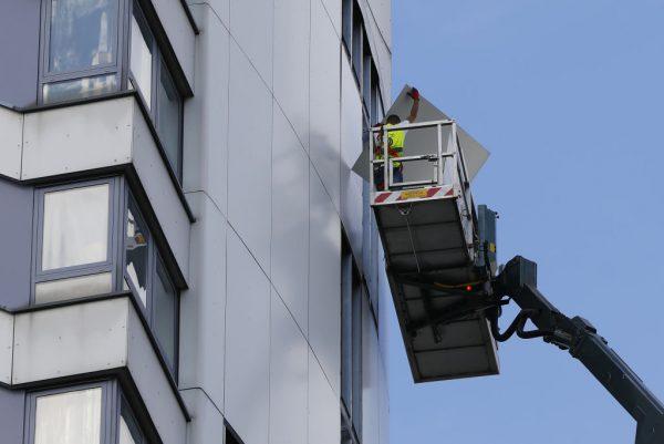 Workers remove panels of external cladding from the facade of Braithwaite House in London, on July 3, 2017, in the wake of the Grenfell Tower fire. (Tolga Akmen/AFP/Getty Images)