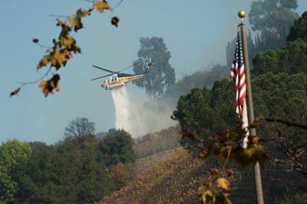 A helicopter drops water on a vineyard owned by Rupert Murdoch damaged by the Skirball fire near the Bel Air neighborhood on the west side of Los Angeles, California, U.S., December 6, 2017. (Reuters/Andrew Cullen)