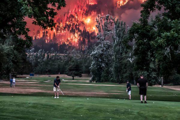 The Eagle Creek wildfire burns as golfers play at the Beacon Rock Golf Course in North Bonneville, Washington, September 4. (Reuters/Kristi McCluer)