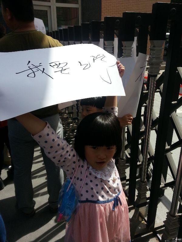 A young girl holds a sign saying, "I want to go to school," in protest of restrictions on education for the children of migrant workers in Beijing, on May 25, 2014. (Boxun.com)