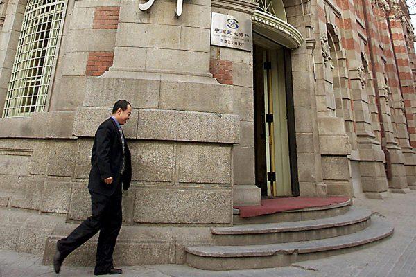 A man walks by the head office of China's largest private lender, Minsheng Bank, in Beijing, on Feb. 25, 2002. (AFP/Getty Images)