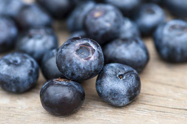 Blueberries on a wooden table; focus on single blueberry (Shallow DOF)