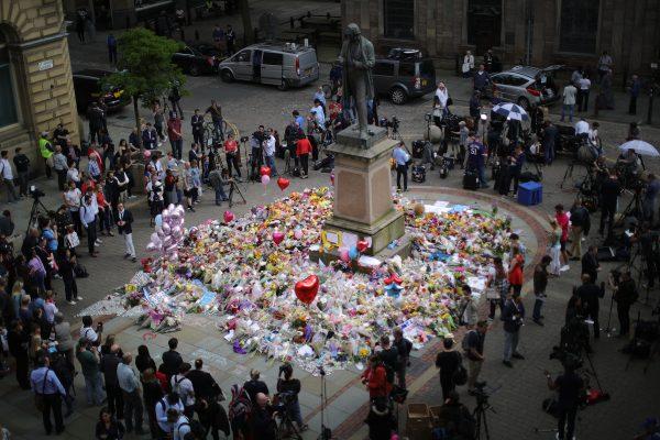 People gather around floral tributes to the victims of the Manchester terror attack ahead of a vigil in St. Ann's Square in Manchester, England, on May 24, 2017. An explosion at Manchester Arena on the night of May 22 at an Ariana Grande concert caused at least 22 fatalities. (Christopher Furlong/Getty Images)