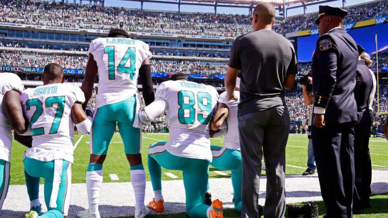 Maurice Smith No. 27 and Julius Thomas No. 89 kneel with Jarvis Landry No. 14 of the Miami Dolphins during the National Anthem prior to an NFL game against the New York Jets at MetLife Stadium in East Rutherford, N.J., on Sept. 24, 2017. (Steven Ryan/Getty Images)