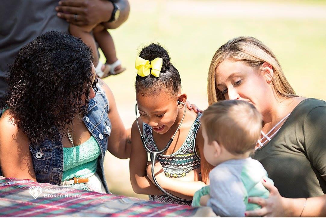 Lacey Tiara Wilcox's daughter listens to the heartbeat of Mason Perkins in Centennial Park in Nashville, Tenn., on Sept. 25, 2017. Mason received the heart of Wilcox's late daughter Alaiya in a transplant. (Suha Dabit/World of Broken Hearts)