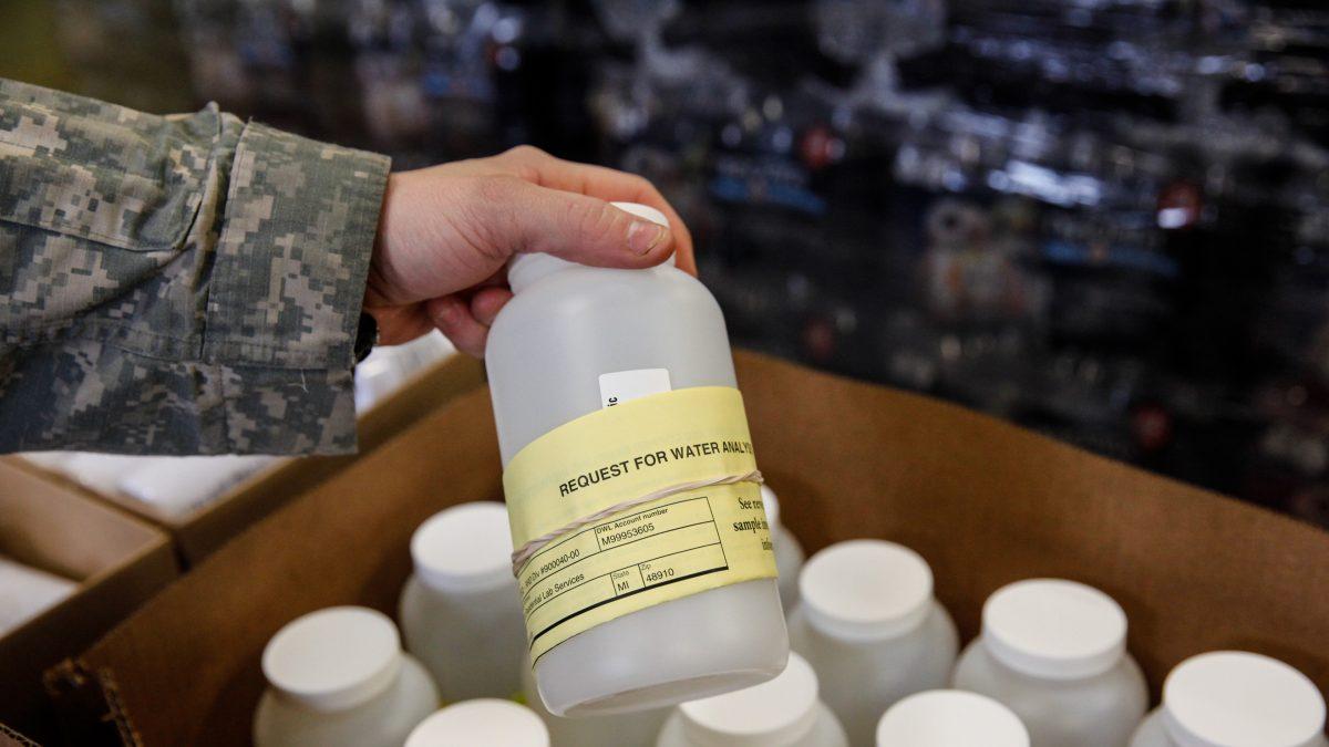 A National Guard soldier looks at a bottle containing contaminated water headed for testing in Flint, Mich., on Jan. 21, 2016. (Sarah Rice/Getty Images)