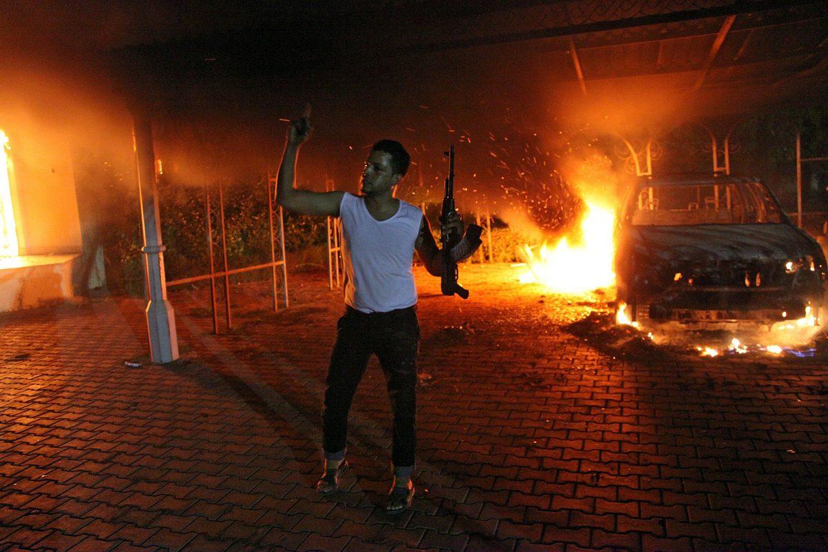 An armed man waves his rifle as buildings and cars are engulfed in flames after being set on fire inside the U.S. Consulate compound in Benghazi, Libya, on Sept. 11, 2012. (STR/AFP/GettyImages)