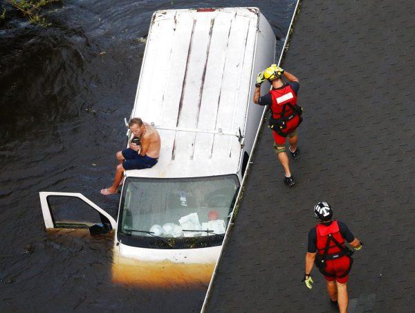 Rescue swimmers approach man stranded on van in Pollocksville, N.C. on Sept. 17, 2018. (AP Photo/Steve Helber)
