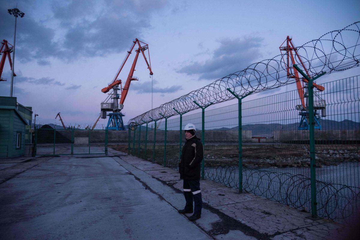 A Russian worker stands before a fence at the RasonConTrans coal port at Rajin Harbor, in the Rason Special Economic Zone, North Korea, on Nov. 21, 2017. A mountain of North Korean coal that would once have been bound for China is stranded by a UN ban on Pyongyang's coal exports. (ED JONES/AFP/Getty Images)