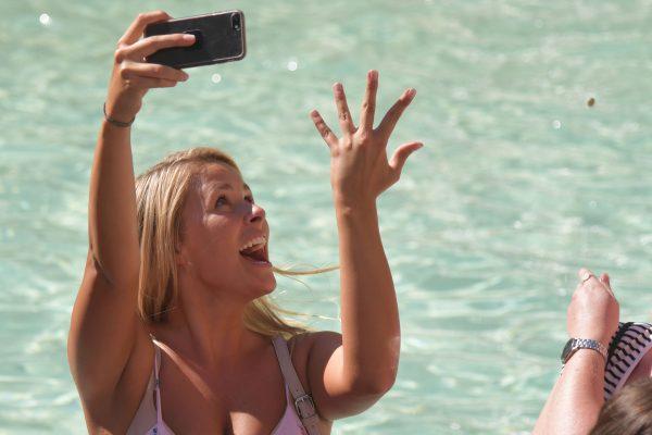 A woman snaps a selfie as she throws a coin in the Trevi Fountain in Rome on June 21, 2017. (Tiziana FabiAFP/Getty Images)