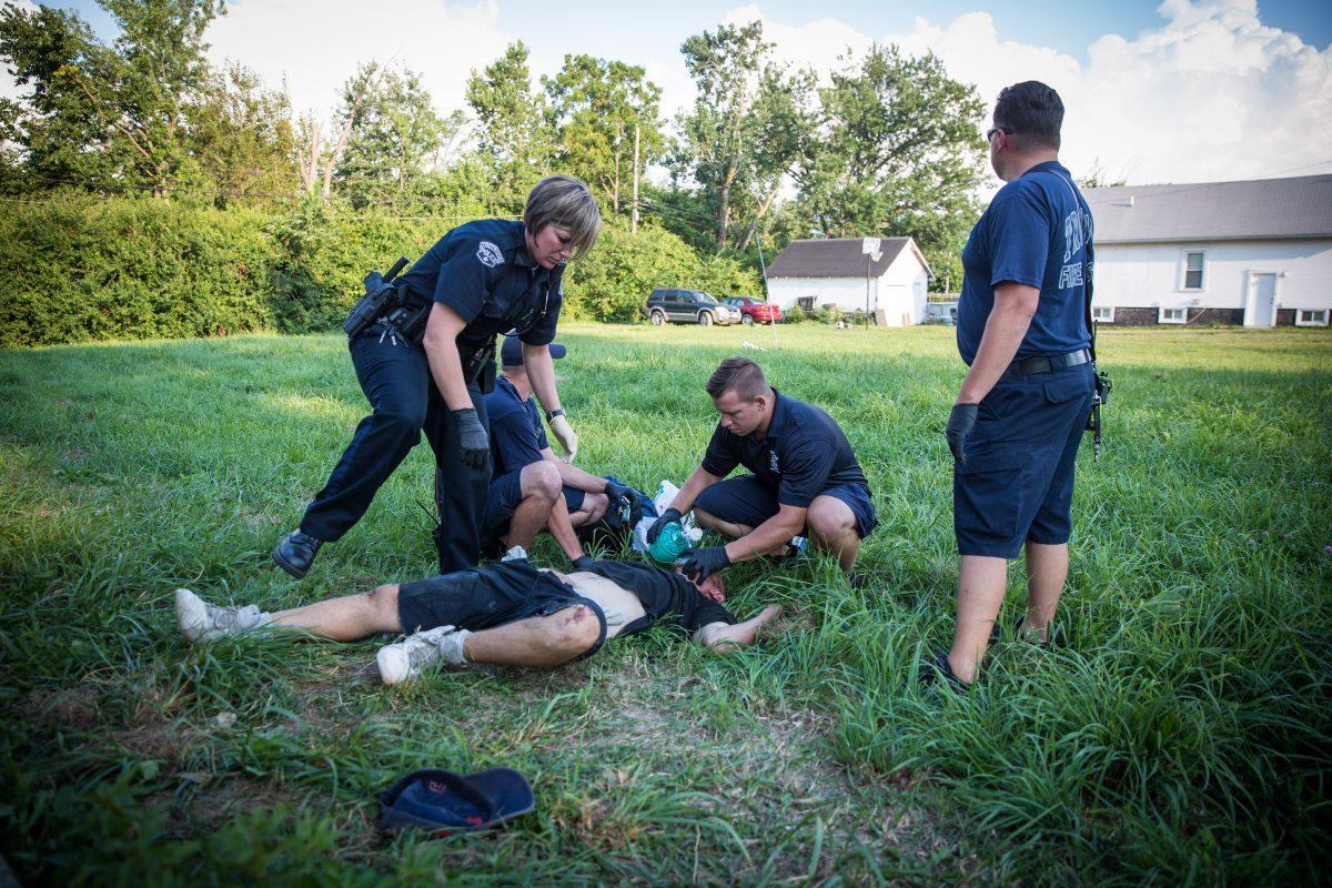 Local Police and paramedics help a man who is overdosing in the Drexel neighborhood of Dayton, Ohio, on Aug. 3, 2017. (Benjamin Chasteen/The Epoch Times)