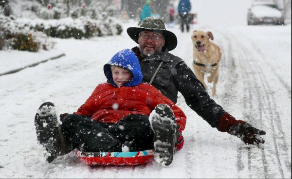 Beckett Luthi, 9, and his father Chris Luthi sled near their home in West Seattle on Feb. 8, 2019. (Erika Schultz/The Seattle Times via AP)