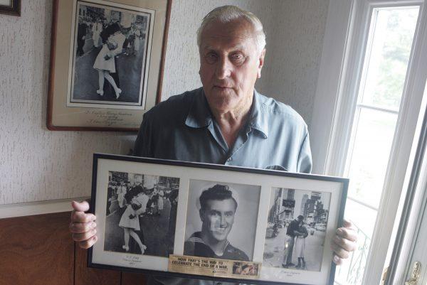 George Mendonsa poses for a photo in Middletown, R.I., on July 2, 2009, holding a copy of the famous Alfred Eisenstadt photo of Mendonsa kissing a woman in a nurse's uniform in Times Square on Aug. 14, 1945, while celebrating the end of World War II, left. Mendonsa died Feb. 17, 2019, he was 95. (Connie Grosch/Providence Journal via AP)