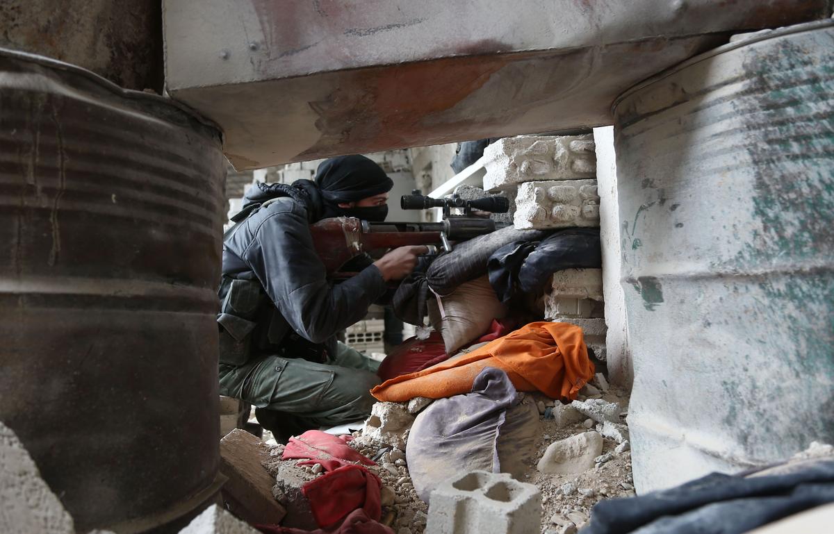An unidentified Syrian opposition fighter looks through the scope of a sniper rifle as he sits behind cover in a damaged building on the frontline in the rebel-held enclave of Arbin in the Eastern Ghouta near Damascus on Feb. 15, 2018. (Abdulmonam Eassa/AFP/Getty Images)