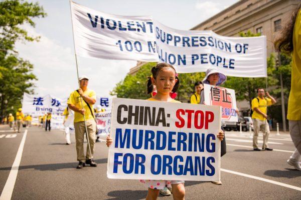 A young Falun Dafa adherent holds a sign asking for China to stop killing prisoners of conscience for their organs in a parade in Washington on July 20, 2017. (Benjamin Chasteen/The Epoch Times)