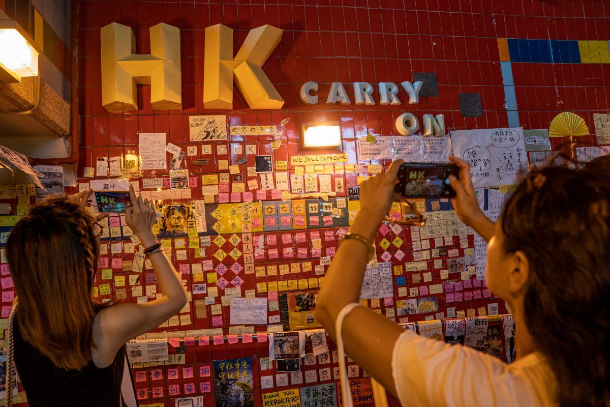 Pedestrians take photos at a makeshift "Lennon Wall" covered with handwritten messages to show support for the pro-democracy protesters, inside an underground tunnel at Tai Po district in Hong Kong, China, on July 20, 2019. (Anthony Kwan/Getty Images)