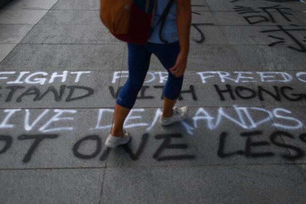 A student walks past graffiti spray-painted on the pavement at the Chinese University of Hong Kong (CUHK) in Hong Kong on Oct. 3, 2019. (Mohd Rasfan/AFP via Getty Images)